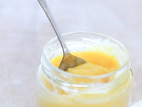 Prepared lemon curd in a jar with a spoon