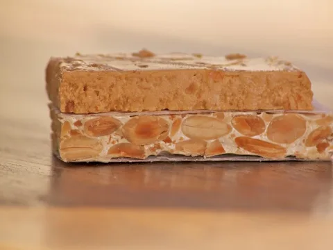 Hard almond turrón alongside soft turrón on a wooden board
