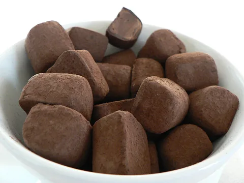 A white bowl of unwrapped cocoa-coated Lindt chocolate truffles