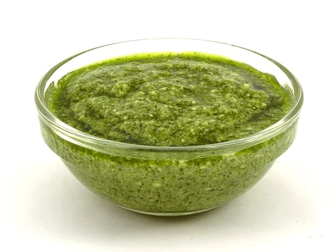 Green basil pesto in a clear bowl