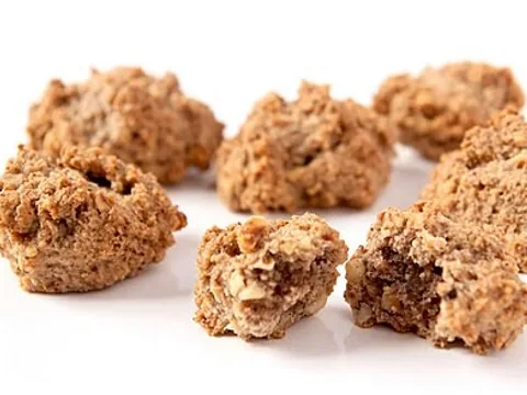 Golden nut-studded brutti ma buoni biscuits on a white surface