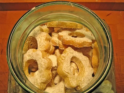 Sugar-dusted flower-shaped canestrelli biscuits in a glass dish