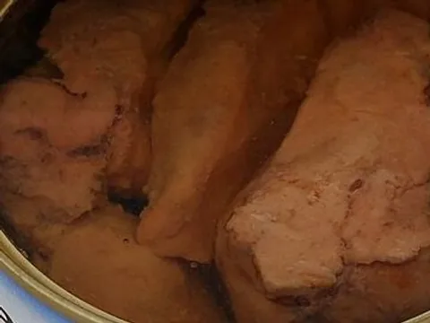 Canned cod liver pieces visible in an opened tin