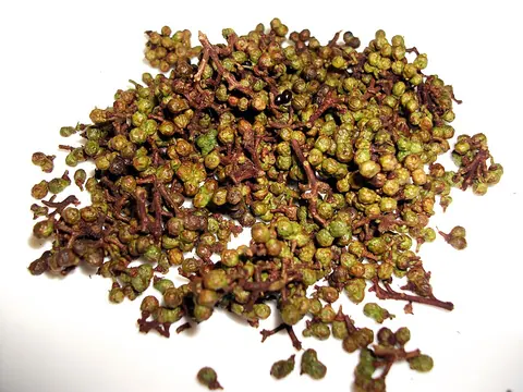 Whole andaliman berry clusters on a plain white background