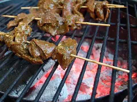Beef-heart skewers grilling over hot coals