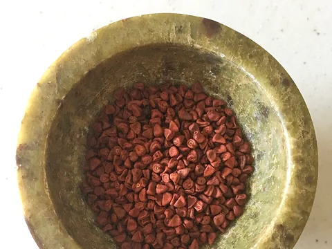Whole dried annatto seeds in a mortar