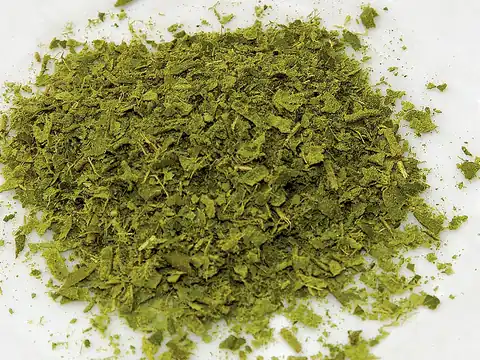 Dried crushed lemon myrtle leaves on a white background